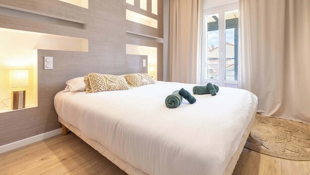 Une chambre d’hôtel avec un grand lit, une lampe fixée au mur et une vue sur l’extérieur.