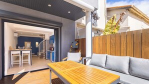 Une terrasse en bois avec une table et un canapé, un escalier menant à un niveau supérieur et une vue sur le ciel.
