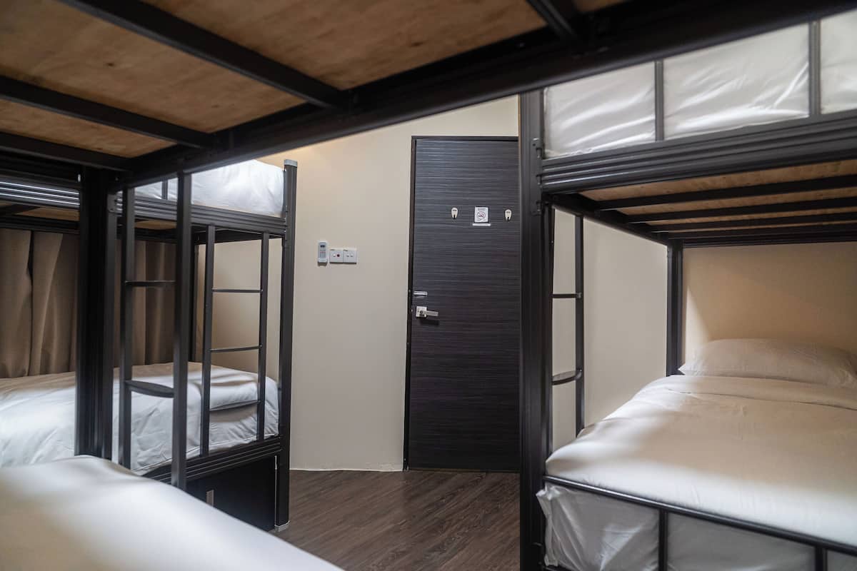 A bunk bed room with a door and a light switch on the wall.