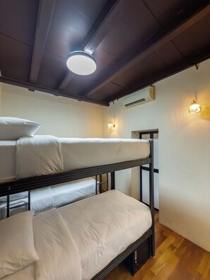 Habitación con literas dobles, una lámpara en el techo, luces en la pared y un equipo de aire acondicionado.