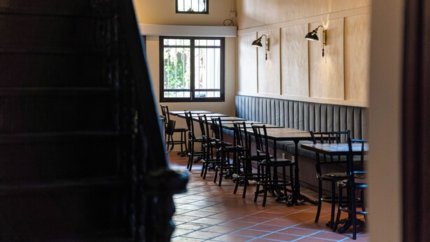 L’intérieur d’un restaurant, avec des tables et des chaises, une fenêtre donnant sur un paysage et une lampe fixée au mur.