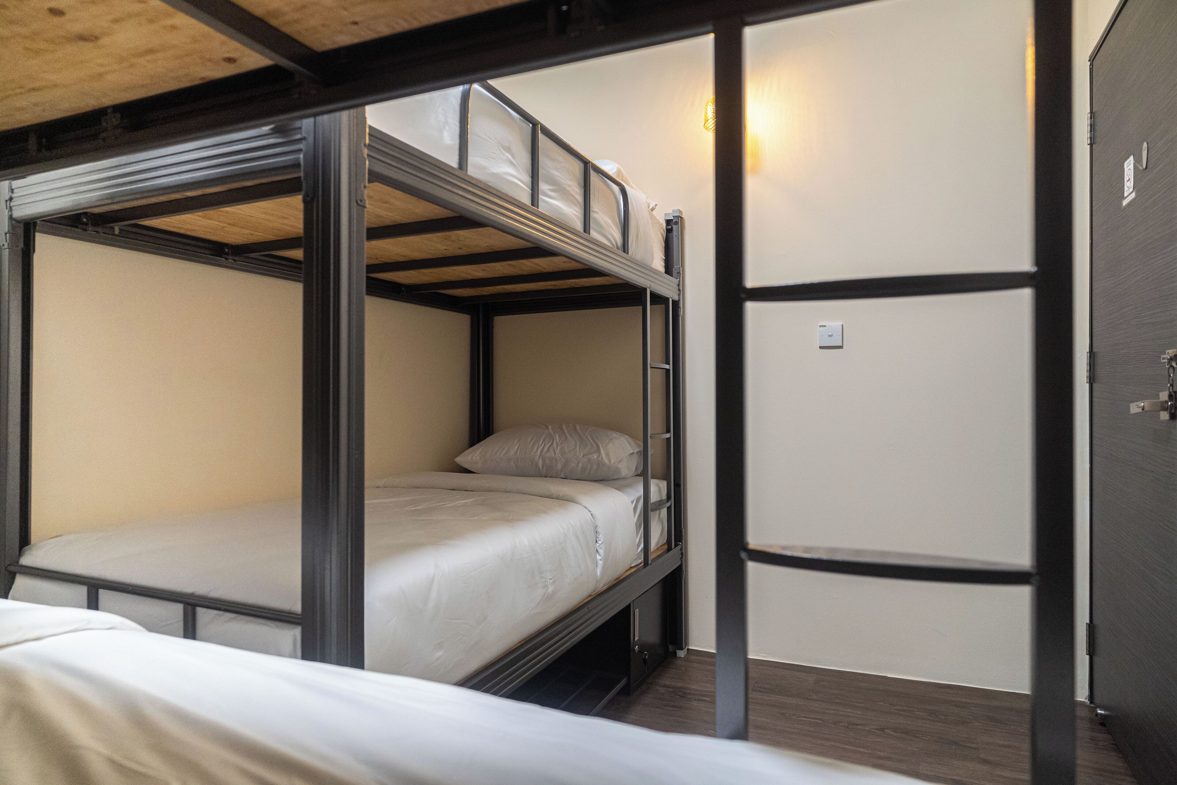 A bunk bed room with a wooden ceiling and a door on the right.