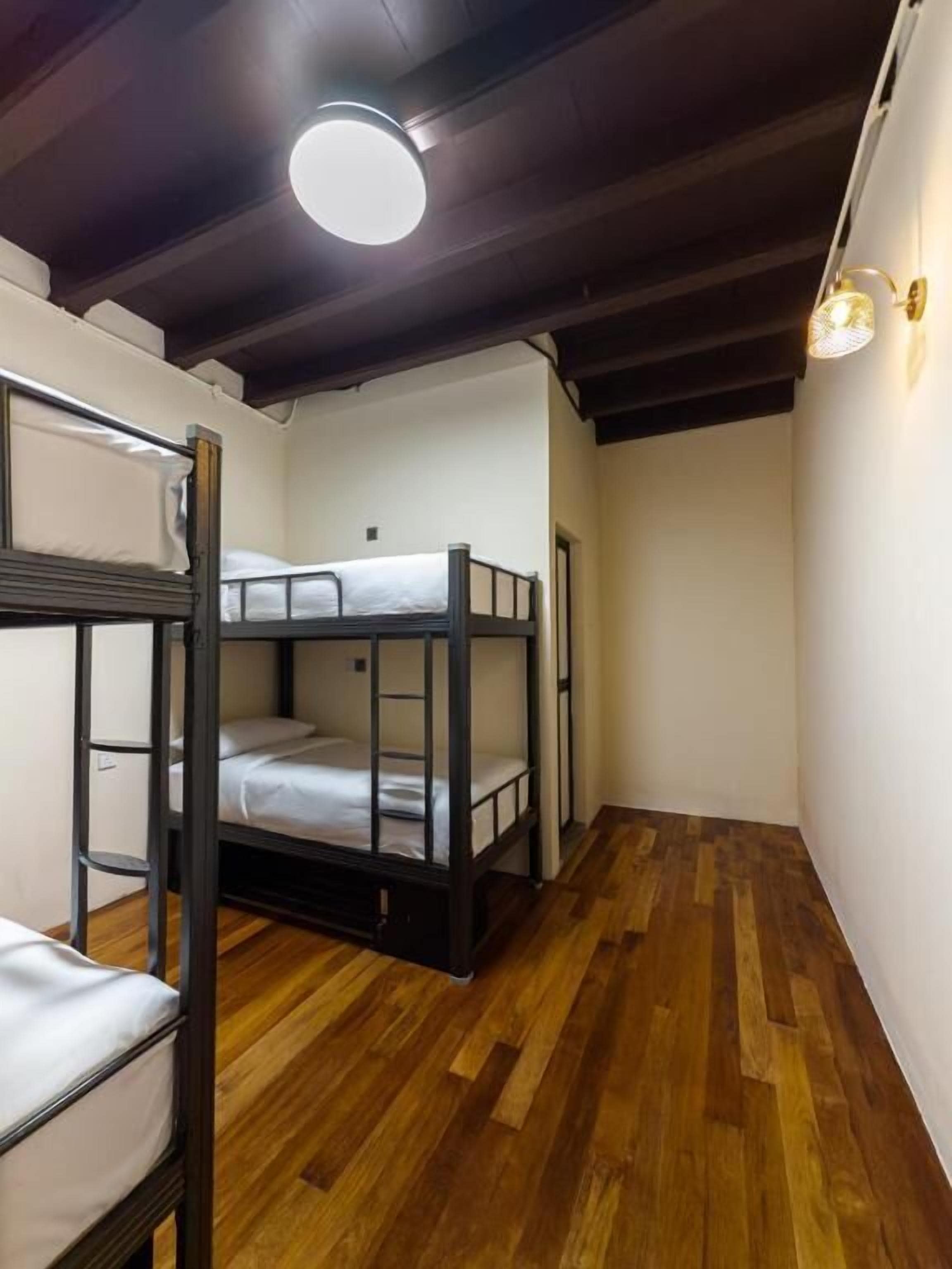 A narrow room with bunk beds and a wooden floor.