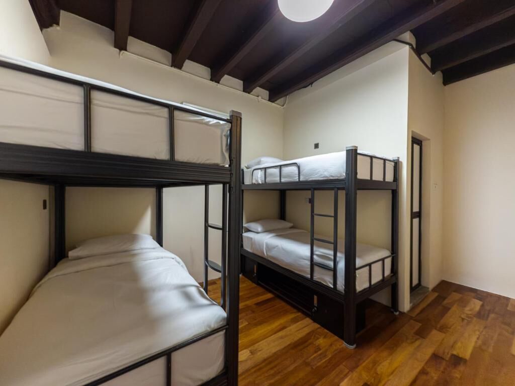 A room with three bunk beds, wooden flooring, and a circular light fixture on the ceiling.