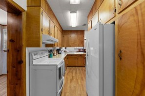 Une cuisine avec des meubles de rangement en bois, une cuisinière blanche et un réfrigérateur.