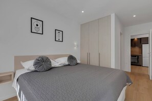 A modern bedroom with a large bed, a wardrobe, and a kitchenette visible in the background. - Apartment Roza, a beautiful new apartment with parking (Makarska)
