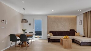 Ein modernes Wohnzimmer mit Essbereich, einer Sofagarnitur und einem Holztisch.