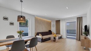 Ein modernes Wohnzimmer mit einer Couch, einem Esstisch, Stühlen und einem Couchtisch.
