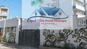 Une enseigne d’hôtel avec un logo représentant une maison, des palmiers et un bateau.