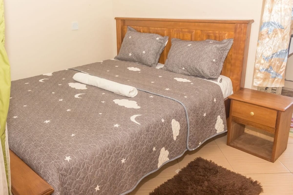 A bedroom with a bed, pillows, a nightstand, and a rug.