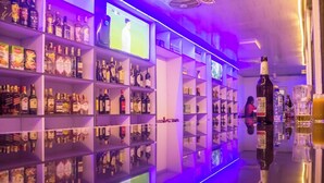 Un bar avec des étagères remplies de bouteilles d’alcool et un écran de télévision.
