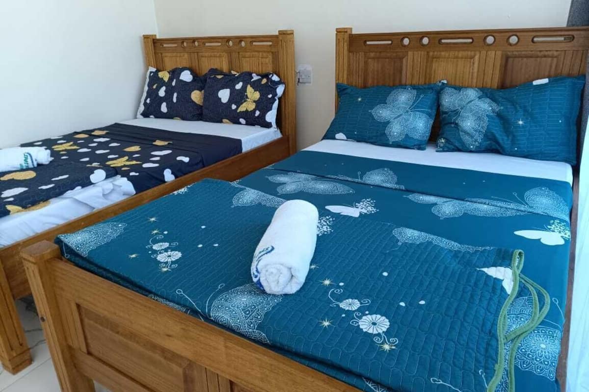 Two wooden beds with matching headboards, each with a patterned bedspread and pillows.