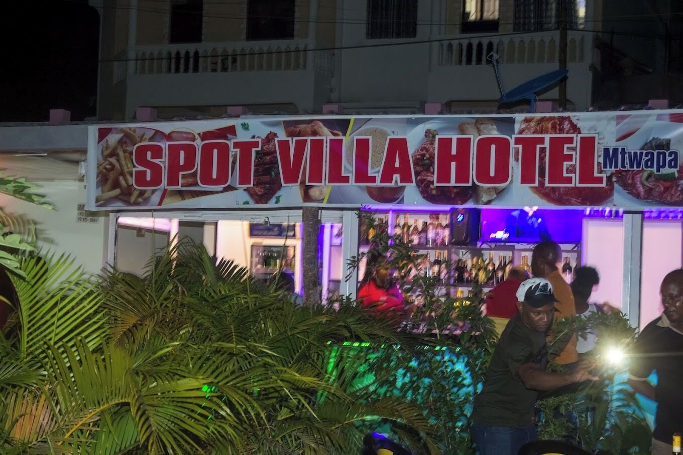 Un hôtel appelé SPOT VILLA HOTEL, dont l’enseigne affiche une liste de plats proposés.