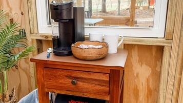 Een houten tafel met een koffiezetapparaat, een kopje en een mand. Onder de tafel staat een Jackery Explorer 1000 power station.