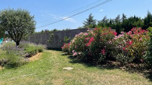 A garden with a stone wall, flowering plants, and a tree. - Country house surrounded by lavender fields and vineyards (Grignan)