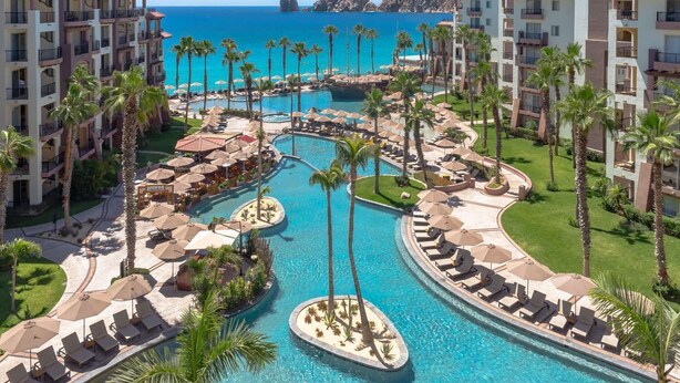 Un resort con diverse piscine, palme e vista sulla spiaggia.