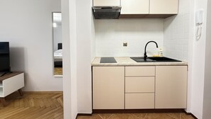 Une cuisine compacte avec des meubles blancs, un évier noir et une hotte intégrée.