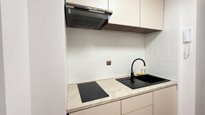 Une cuisine avec un évier noir, une cuisinière encastrée et un dosseret de carrelage blanc.