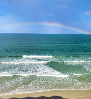 A beach with waves and a rainbow in the sky. - Breath taking   2-bedroom oceanfront condo in tranquil Daytona Beach Shores (Daytona Beach Shores)