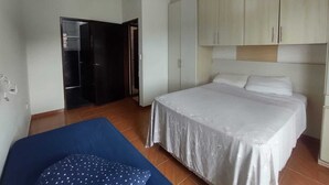 Une chambre à coucher avec un lit, une armoire et un canapé bleu.