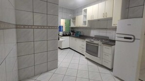 Une cuisine avec des meubles blancs, une cuisinière, un four et un réfrigérateur.