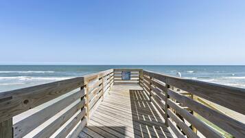 A wooden pier leading to the ocean with a signboard in the center.