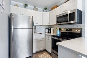 Una cocina moderna con electrodomésticos de acero inoxidable, armarios blancos y salpicadero de azulejos.