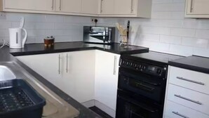 Eine Küche mit weißen Schränken, einer schwarzen Arbeitsplatte, einer Kaffeemaschine, einem Toaster und einem Backofen.