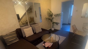 Ein modernes Wohnzimmer mit einem Ecksofa, einem Glastisch und einem Blumentopf.