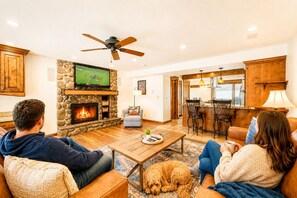 A living room with a fireplace, a television, and a dog. - Park City Family Retreat | Hot Tub | Pet Friendly 177 (Park City)
