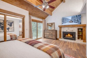 A spacious bedroom with a large bed, a wooden ceiling, a fireplace, and a television on the wall. - Park City Family Retreat | Hot Tub | Pet Friendly 177 (Park City)