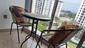 Ein Balkon mit Blick auf eine Stadtlandschaft, mit zwei Korbstühlen und einem kleinen Tisch.