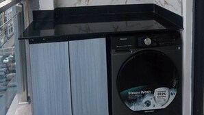 Eine kompakte Küche mit schwarzem Arbeitsplatz, einer integrierten Waschmaschine und einer Marmor-Spritzschutzwand.
