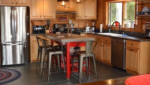 A modern kitchen with wooden cabinets, stainless steel appliances, and a central island with bar stools.