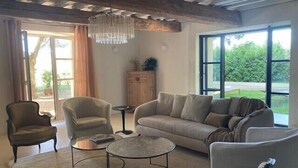 Ein Wohnzimmer mit Sofa, zwei Sesseln, einem Couchtisch und einer Chandelier.