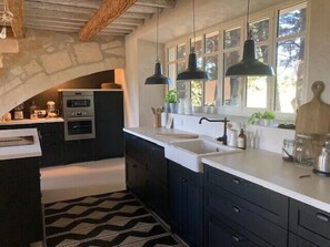 Una cocina moderna con armarios oscuros, encimera blanca y un arco de piedra.