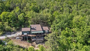 Ein Haus mit einer Terrasse und einem kleinen Boot, umgeben von dichtem Wald.