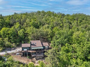 Ein Haus mit einer Terrasse und einem kleinen Boot, umgeben von dichtem Wald.