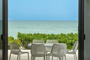 A table with four white chairs facing a view of the ocean. - Enjoy the beach and the sunset in this beautiful beachfront home (Chuburná)