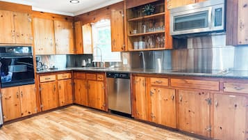 Une cuisine dotée de meubles en bois, d’appareils électroménagers en acier inoxydable et d’un plancher à motifs en chevrons.