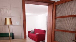 Ein Zimmer mit einem Holztisch, einem roten Sofa und einer Holztür mit Glasfenstern.