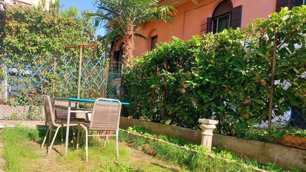 Ein Garten mit Tisch und Stühlen, einem Steinpflanzgefäß und einem Zaun.