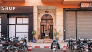 A building with a shop on the ground floor and a residence above. There are several parked scooters in front.