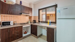 A kitchen with dark wooden cabinets, a microwave, a gas stove, and a white refrigerator.