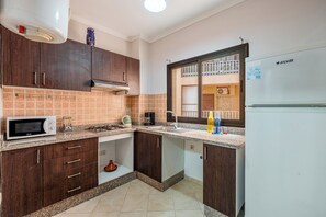 Une cuisine avec des meubles de rangement en bois foncé, un four à micro-ondes, une cuisinière à gaz et un réfrigérateur blanc.