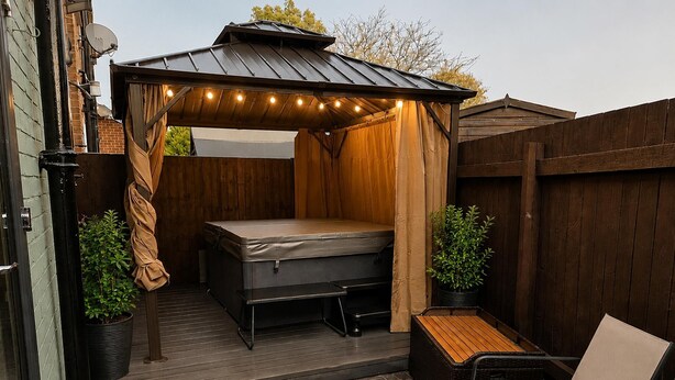 A covered outdoor sleeping area with a bed, a bench, and two potted plants. - Chester Charm - Spacious 3 Bedroom House (Chester)