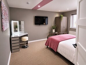 A bedroom with a bed, a desk with a chair, a TV, a wardrobe, and a window. - The Cloud House Spa Retreat Hoole (Chester)