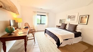 Un dormitorio con una cama grande, un escritorio con un globo terráqueo, una silla y una ventana con cortinas.