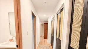 Un pasillo con piso de madera, un tapete tejido y puertas con diseño perforado.