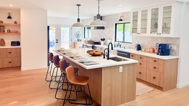 A modern kitchen with a central island, bar stools, pendant lighting, and a large window. - Ojai Valley Luxury Hillside Estate (Ojai)